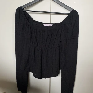 Svart långärmad blus från SO - Svart blus från SO med lång ärm och lätt rynkad struktur. Modellen har en bred, rundad halsringning och faller snyggt med en lite lösare passform. Perfekt för dig som gillar en enkel men trendig look.knappt använd.