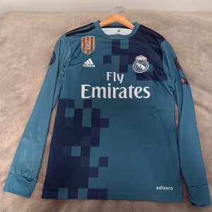 Ronaldo Real Madrid långärmad tröja  - Säljer en långärmad Real Madrid fotbollströja från Adidas med Ronaldo 7 på ryggen. Tröjan är blå med mörkblå pixelmönster, broderat klubbmärke och Champions League-patch på ärmen. Tillverkad i lätt och ventilerande ClimaCool-material. pris kan diskuteras
