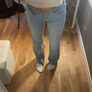 Ljusblå bootcut jeans - Säljer ett par ljusblå jeans med bootcut passform och låg midja. Jeansen har klassisk femficksdesign och är tillverkade i mjukt denimtyg. Perfekta för dig som gillar en avslappnad och trendig look. De är lågmidjade med slits längst ner på byxorna 