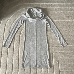 Ljusgrå ribbad klänning Gina Tricot - Supersnygg ljusgrå ribbad klänning från Gina Tricot i figurnära modell. Klänningen har lång ärm, polokrage och är tillverkad i mjuk bomullsblandning. Perfekt för dig som gillar enkel och stilren look med en twist.