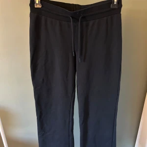 Mörkblå mjukisbyxor med snörning - Mörkblå mjukisbyxor med rak passform och snörning i midjan. Perfekta för chill dagar eller när du vill vara bekväm. Tillverkade i mjukt material som känns skönt mot huden.