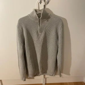 Grå stickad half zip-tröja från Zara - Säljer en stilren grå stickad tröja från Zara med hög krage och half zip-dragkedja. Tröjan har lång ärm och är ribbstickad för en snygg och bekväm look. 