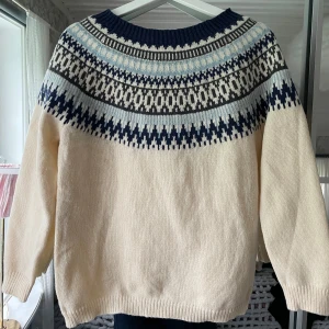Mönstrad stickad tröja i blått och vitt - Säljer en mysig stickad tröja med klassiskt mönster i marinblått, ljusblått, vitt och grått. Tröjan har rund halsringning och ribbade muddar. Använd fåtal gånger, mycket bra skick.