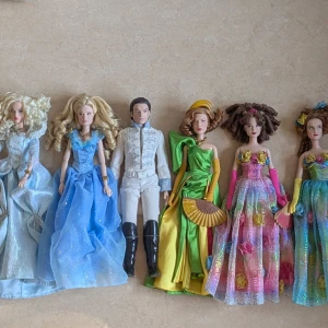 DISNEY ASKUNGEN, UNIK SAMLING DOCKOR - Unik samling av sex dockor från filmen Disney Askungen. Askungen har en magisk blå prinsessklänning med glittrande tyll och voluminös kjol. Klänningen har en överdel med volangdetaljer och är ärmlös. Disney dockorna har alla underbart vackra klänningar utom prinsen som är vackert kläd som en prins. Alla dockorna har skor som medföljer. Dockorna har använts som dekoration.