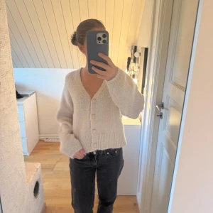 Vit/beige stickad kofta från ONLY - Mysig vit/beige stickad kofta från ONLY i storlek M. Koftan har v-ringning, ribbade muddar och knappar framtill. 