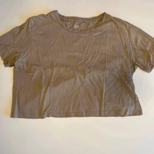 Beige croppad t-shirt från 157 - En basic beige croppad t-shirt från Lager157 i 100% bomull. T-shirten har rund halsringning och korta ärmar, perfekt för en avslappnad och enkel stil. Passformen är loose och materialet är mjukt och skönt mot huden.