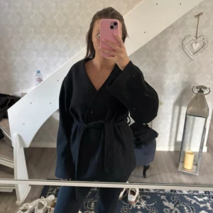 Svart kort kappa - Super snygg svart kort kappa i storlek xs. Jag är 165💕 bälte i midjan. Nypris 799kr