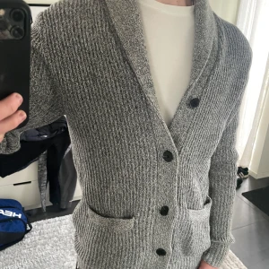 Grå stickad kofta från HM - Snygg grå stickad kofta från H&M i storlek M, modellen är ca 180cl lång. Hör av dig vid funderingar!