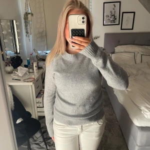Grå stickad tröja från Vero Moda - Mysig grå stickad tröja från Vero Moda i storlek XS. Tröjan har rund halsringning, ribbade muddar och lång ärm. Perfekt för lager-på-lager och enkel att matcha med jeans eller kjol. Klassisk och stilren modell som funkar året runt.