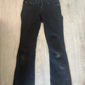 Svarta bootcut jeans från Perfect Jeans - Svarta jeans från Perfect Jeans i bootcut-modell med snygga bakfickor med lock och silverfärgade knappar. Jeansen har klassisk femficksdesign och är tillverkade i ett stretchigt bomullsmaterial för skön passform.