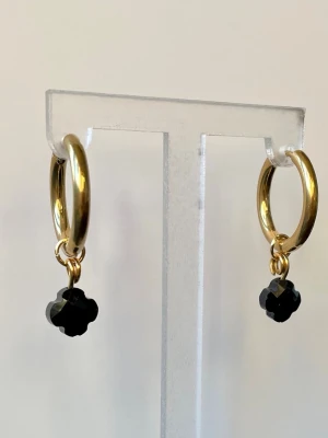 NYTT stainless Steel örhängen  - Bilderna visar ett par guldfärgade örhängen med svart blomformad hängande detalj, men ingen väst finns med.