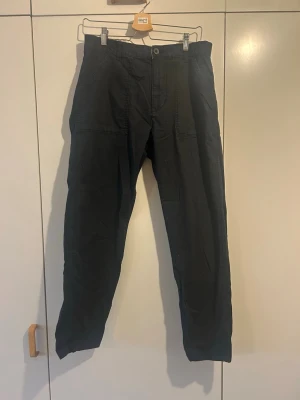 Svarta cargopants från Vailent, L - Svarta cargopants från Vailent i storlek L. Byxorna har stora fickor framtill, klassisk midja och raka ben. Materialet är slitstark bomull med diskret rutmönster i tyget. Perfekt för dig som gillar streetwear och funktionella detaljer.