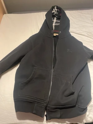 En svart burberry zip up hoddie - En svart zip upp hoddie som har väldigt bra kvalitet och den är endast använd 2 gånger