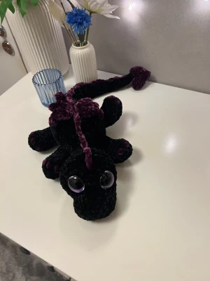 Svart drake med lila detaljer🖤💜 - Denna söta drake letar efter sitt nya framtida hem🖤💜🐉 Denna är virkad med kärlek, jag älskar att virka💜 Den är virkad av mjukt garn från Rusta, hårda ögon som inte går att ta av. Den är 56cm lång och man sträcker ut svansen🐉