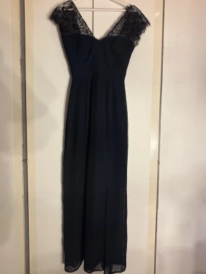 Balklänning!💙 - Säljer denna superfina och Eleganta marinblå långklänning med v-ringad hals och spetsdetaljer vid axlarna. Klänningen har en slits framtill som ger extra rörelsefrihet och ett sofistikerat uttryck. Materialet är lätt och flytande, perfekt för speciella tillfällen som balen. Spetsen ger en romantisk touch. Tyvärr har klänningen råkat få ett hål i ytter tyget, men väldigt lätt fixat med nål och tråd! Men utöver det så är den i bra skick, I storlek 36