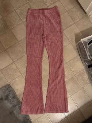 Rosa manchesterbyxor från KappAhl - Säljer ett par snygga rosa manchesterbyxor från KappAhl i storlek 164. Byxorna har hög midja, utsvängda ben och ribbad struktur som ger en retrovibe. Perfekta för dig som vill ha något bekvämt men ändå trendigt.