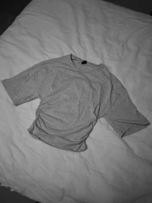 Grå t-shirt från Gina Tricot - Snygg grå t-shirt från Gina Tricot i storlek S. Modellen har medel långa ärmar och cool snörningsdetalj på sidan som ger en unik look. Mjuk och skön, perfekt till jeans eller kjol. Enkel att styla och passar dig som gillar trendiga basplagg.💕