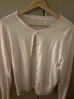 Ljusrosa kofta från Holly & Whyte - Säljer en ljusrosa kofta från Holly & Whyte by Lindex i storlek M. Koftan har rund hals, långa ärmar och guldfärgade knappar framtill. Materialet är mjukt och stickat. Inte alls stickig! Originalpris 350. Använd 1 gång så inga defekter!!