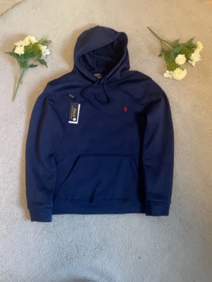 Ralph lauren hoodie i navyblå  - Jag säljer en snygg och ny Ralph Lauren hoodie i navyblå färg, perfekt för både vardag och träning! Hoodien är i storlek S och kommer med taggarna kvar, så den är använd ett par gånger. Den är både bekväm och stilren, vilket gör den lätt att matcha med både jeans och träningsbyxor. Jag vill också poängtera att jag är aktiv och snabbt skickar hoodien samma dag eller dagen efter köpet, så du kan få din nya favoritplagg på nolltid! Passa på att köpa denna kvalitetsprodukt till ett bra pris.