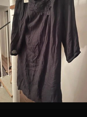 Black Tunic Dress with Lace Detail - Elegant black tunic dress with beautiful lace detailing around the neckline. Made from a lightweight, slightly textured fabric that drapes nicely and is comfortable to wear. • Brand: Cappuccini • Color: Black • Size: EU 36 • Style: Tunic / short dress • Sleeves: 3/4 length • Condition: New with tag (original price 499 SEK) Perfect for everyday wear, work, or dressed up for an evening out. Easy to style with leggings, tights, or jeans. Let me know if you have any questions! 😊 