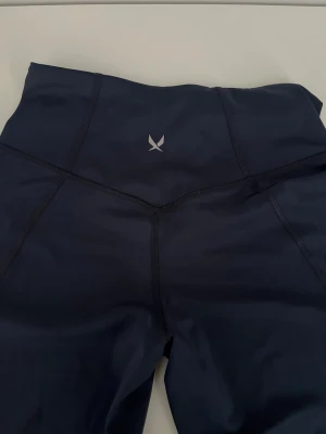 Mörkblå yogabyxor från SOC XS - Snygga marinblå yogabyxor från SOC i storlek XS. De är i helt nytt skick eftersom jag använde de bara en gång där jag då insåg att de var tyvärr för korta på mig. De är midwaist och är gjorda i ett stretchigt syntetmaterial med TCS Airflow-teknologi som håller dig torr och bekväm. Perfekta för träning eller chill. 