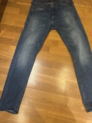 Replay Grover blå jeans, storlek 31/32 - Säljer ett par Replay Grover jeans i klassisk blå tvätt med snygga slitningar. Modellen har raka ben och normal passform, med Replay-logga på fickan och dragkedja i gylfen. Tillverkade i slitstarkt bomullsmaterial, perfekta till vardagslooken.