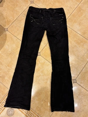 Svarta utsvängda jeans - Säljer mina favoritjeans som tyvärr har blivit för små. Jeansen har silvriga/glittriga detaljer och är utsvängd. Jätteenkla att stylea och är i jättefint skick! Kontakta vid fler frågor❤️