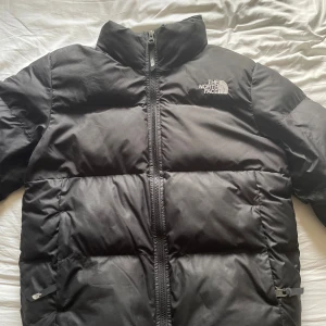The North Face - Säljer en svart pufferjacka från The North Face i dammodell, storlek S. Jackan har hög krage, lång ärm och dragkedja framtill. Den är vadderad och har loggan broderad på bröstet och ryggen. I nyskick, har använts varsamt.💕