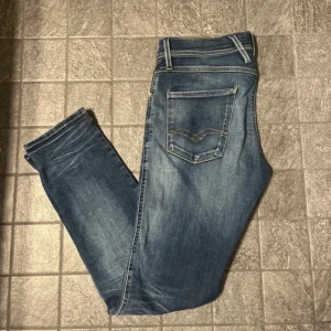Replay Anbass (hyperflex) jeans blå slim fit - Snygga Replay Anbass jeans i blå med slitningar . Slim fit-modell med broderad detalj på bakfickan. Perfekt passform och skön stretch i materialet.                                                                                                                                                    Hör av vid funderingar!