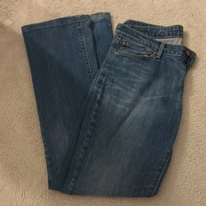 Levi's 501 blå jeans bootcut - Klassiska Levi's 501 jeans i blå tvätt med bootcut passform. Snygga kontrastsömmar och ikoniska bakfickor med Levi's etikett. Jeansen har normal midja och raka ben, tillverkade i slitstarkt bomullsjeansmaterial. Perfekta för en avslappnad och cool stil.