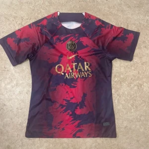 PSG x Nike röd/blå fotbollströja - Säljer en Paris Saint-Germain fotbollströja från Nike med Qatar Airways-logga. Tröjan har ett unikt abstrakt mönster i rött och mörkblått, korta ärmar och PSG-emblem på bröstet. Materialet är lätt och andas, perfekt för träning eller match.