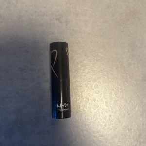 Nude läppstift från NYX - Snyggt nude-färgat läppstift från NYX med klassisk svart hylsa och silvrig detalj. Krämig formula som ger en naturlig look och passar perfekt till alla tillfällen. Enkel att applicera och smidig att ha med i väskan. Testad på handen 