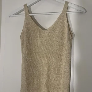 Glittrig guldig linnetopp - Snygg guldig linnetopp med glitter och v-ringning. 