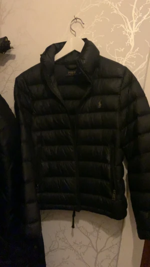 Svart dunjacka Polo Ralph Lauren XS - Svart dunjacka från Polo Ralph Lauren i storlek XS. Jackan har quiltad design, hög krage och två fickor med dragkedja. Klassisk logga på bröstet och stilren look som funkar till allt. Perfekt för kalla dagar och har en snygg, normal passform. Priset kan diskuteras ❤️❤️