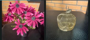 Blommor och äpple  - Konstgjorda blommor i en kruka samt ett dekorativt äpple i metallnät. 