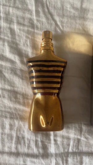 Guldig parfymflaska herr - Snygg och unik parfymflaska i guld med randigt mönster, formad som en torso. Perfekt för dig som vill sticka ut med din stil. Märket är Jean Paul Gaultier.