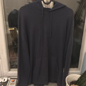 Mörkblå hoodie i kashmir från Massimo Dutti - Snygg mörkblå hoodie från Massimo Dutti i 100% kashmir. Hoddie har ett litet hål vid armen inte jätte synligt och en liten skada vid framsidan på Hoddien. Ny pris på tröjan cirka 1200kr.