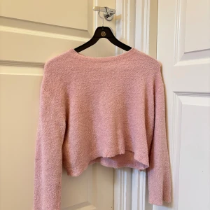 Ljusrosa croppad stickad tröja - Mysig ljusrosa stickad tröja med croppad passform och långa ärmar i storlek S. Tröjan är från pull&bear. Använd ett fåtal gånger men bra skick! Skriv för fler bilder
