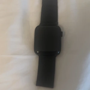 Svart Apple Watch SE 2nd Gen 44 mm GPS - Snygg svart Apple Watch med fyrkantig display och stilrent mesh-armband. Klockan har en minimalistisk design och passar perfekt för dig som gillar tech och vill ha koll på tiden, hälsan och annat med stil. Nypris: 3200kr+