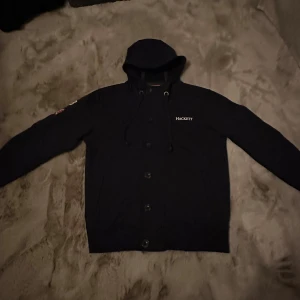 Hackett London huvtröja med knappar  - Väldigt fint skick och en väldigt unik tröja. Den sitter som den ska i storlek. Denna går ej att köpa längre. Hör av dig vid frågor eller intresse