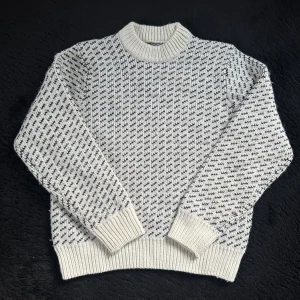 Vit stickad tröja Vailent XS - Snygg stickad tröja från Vailent i storlek XS. Tröjan är vit med svart mönster och har en rund hals samt ribbade muddar vid ärmslut och nederkant. 