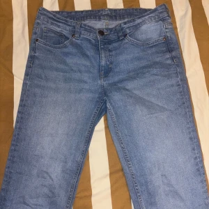 Blå bootcut jeans  - Snygga ljusblå jeans med bootcut passform, fransig kant längst ner på benen. Klassisk femficksmodell med knapp och dragkedja framtill. Jeansen är tillverkade i mjukt denim och har en avslappnad vibe som passar perfekt till sneakers.