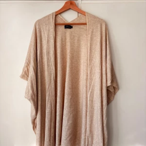 Beige/korall långkofta från Polo Ralph Lauren - Säljer en beige/korall långkofta från Polo Ralph Lauren i mjukt och tunt stickat material. Koftan har en loose passform med öppet framtill och korta ärmar. Perfekt för lager-på-lager och chill stil. Färgen är neutral och passar till allt.