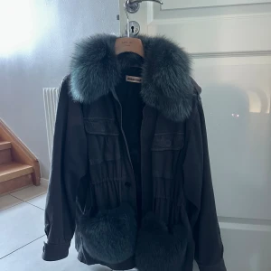 Grå pälsjacka från Custommade - Säljer en grå jacka från Custommade med fluffig pälsdetalj på krage och fickor. Säkjer då den inte kmr till användning