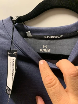 Blå sweatshirt från Under Armour - Snygg blå sweatshirt från Under Armour med diskret logga på bröstet och rund hals. Tröjan har en loose passform och är tillverkad i mjuk polyester, perfekt för chill eller sport. Långärmad modell med stilren look och taggen kvar.ny pris ca 799