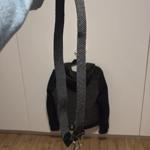 Grå flätat bälte med metallspänne - Snyggt grått bälte med flätad design och robust metallspänne. Bältet har detaljer i svart skinn vid spännet och är perfekt för att ge din outfit en cool touch. Passar till jeans eller chinos och är lätt att justera tack vare den flexibla flätningen.