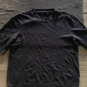 Marinblå tröja från 157 - Marinblå tröja från 157 i storlek S. Tröjan har rund hals och korta ärmar, vilket gör den enkel att matcha med olika outfits. Materialet är mjukt och har en klassisk ribbad kant vid halsen och nederkanten.