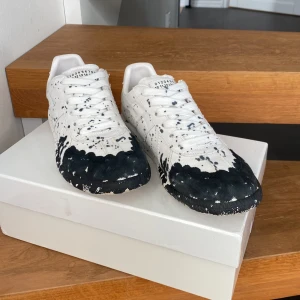 Maison Margiela GATS vita med svart stänk - Maison Margiela sneakers i vitt tyg med svart färgstänk och unikt mönster. Perfekt för dig som vill klä upp dig i vardagen🌟 Hör gärna av dig vid intresse och du är välkommen att ställa frågor🤗 Fler bilder kan skickas✅