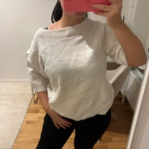 Vit stickad tröja Gina Tricot - Vit stickad tröja från Gina Tricot med bred ribbad halsringning och korta ärmar. Modellen är loose fit och har en mjuk, skön känsla som passar perfekt till jeans eller kjol. Enkel och clean design utan mönster eller detaljer.