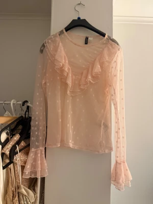 Ljusrosa prickig volangblus  - Superfin ljusrosa blus från Hm i transparent mesh med prickigt mönster. Blusen har volangdetaljer framtill och vid ärmsluten samt långa ärmar. 
